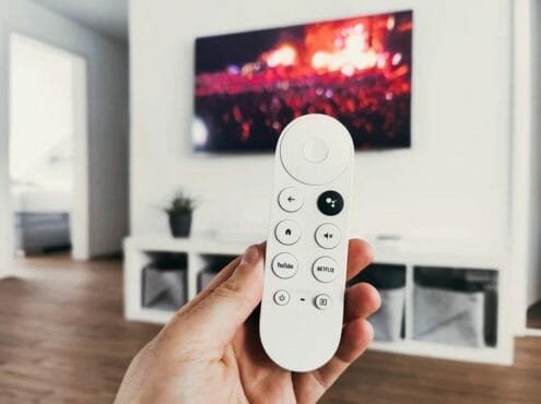 woman's hand holding a white tv remote control