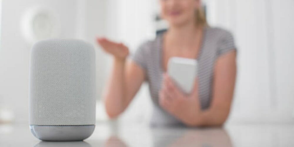 woman holding a phone gesturing to alexa device