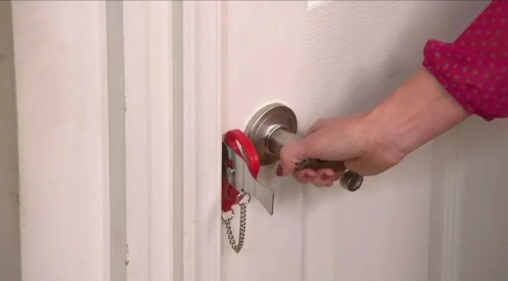 a woman opening the door with the portable door lock