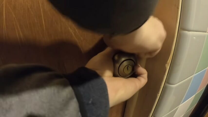 man trying to open the doorknob while inserting the plastic card