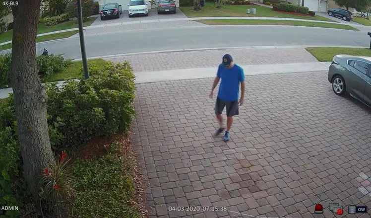 man in blue shirt walking at the sidewalk