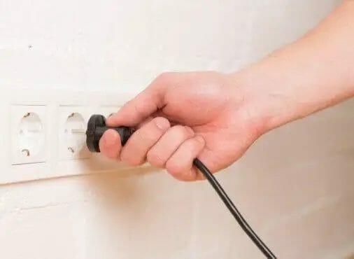hand plugging the power cord into the outlet