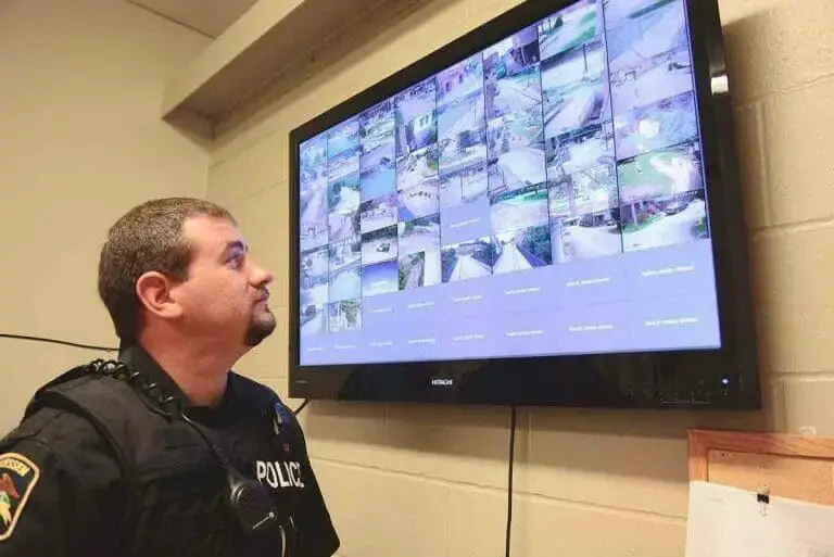 police officer monitoring a cctv live feed on the tv mounted at the wall