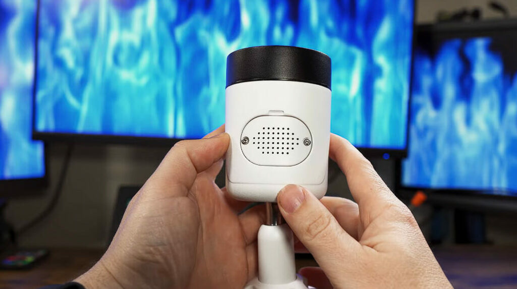 a hand holding a security camera with speaker