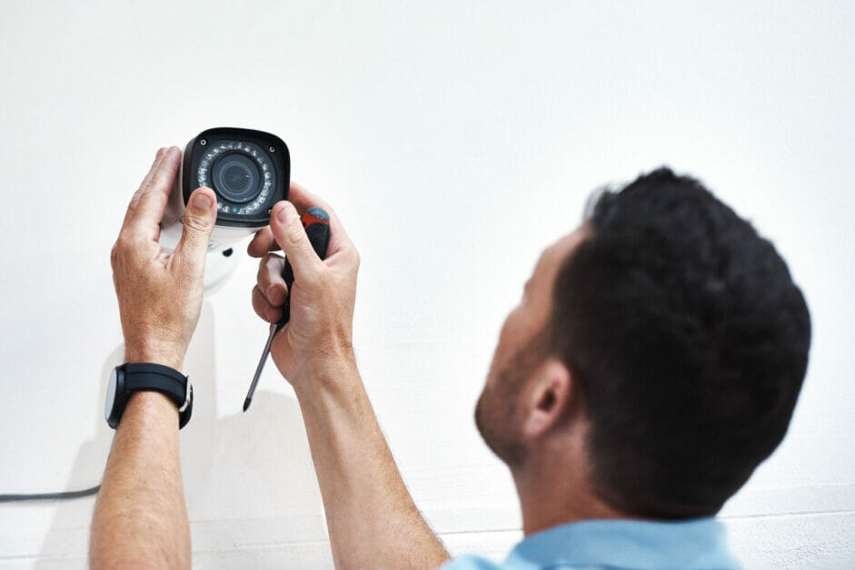 man installing cctv on a white wall