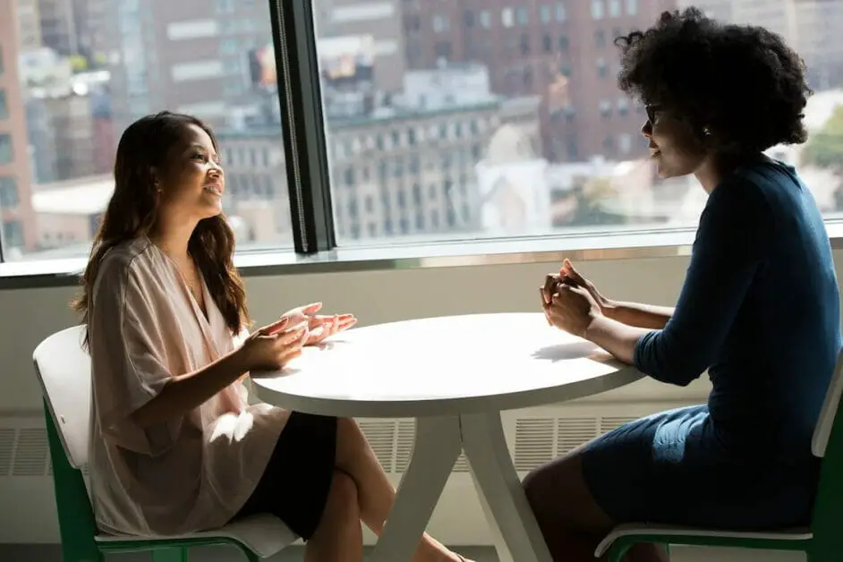 two woman talking in a circular table