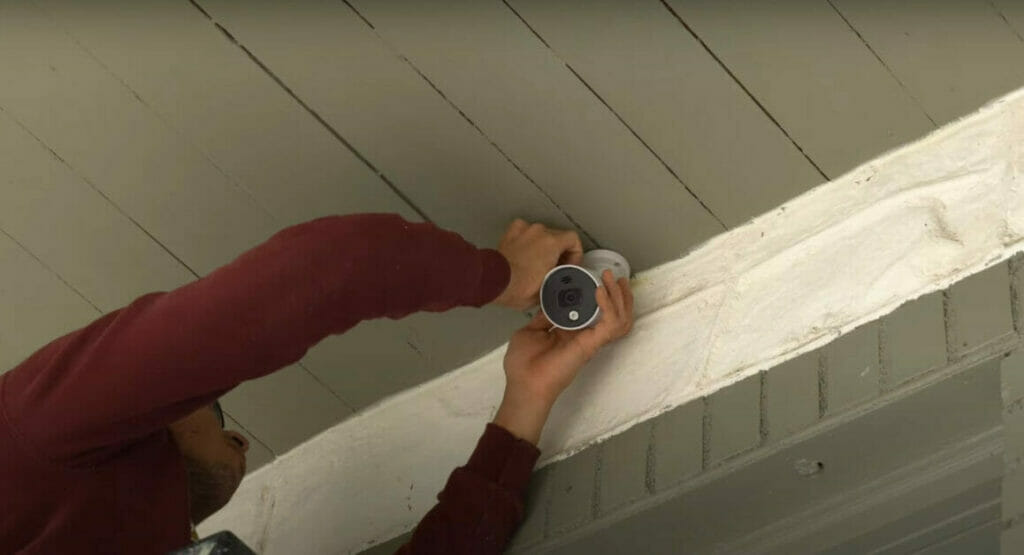 A man easily installs a Night Owl wired security camera on a porch