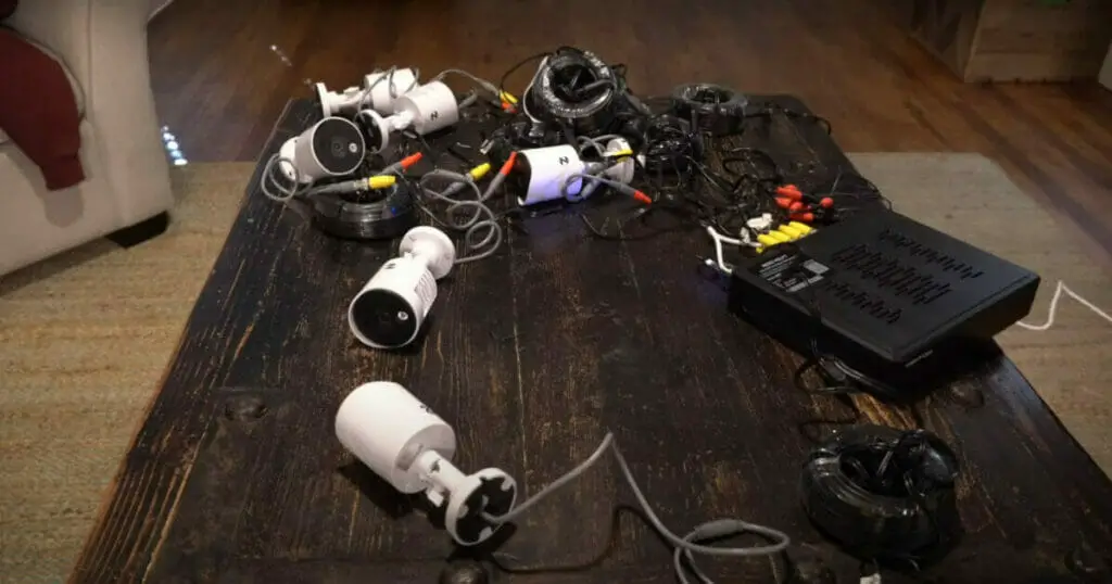 A table with multiple electronics, including Night Owl wired security cameras